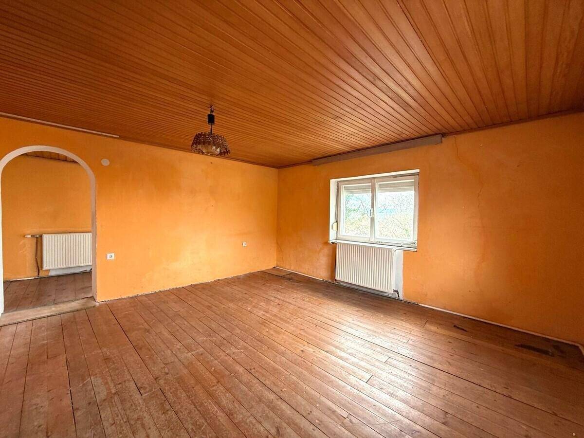 Wohnraum mit leuchtend orangefarbenen Wänden, Holzdielenboden und einer Holzpaneeldecke im Landhausstil.