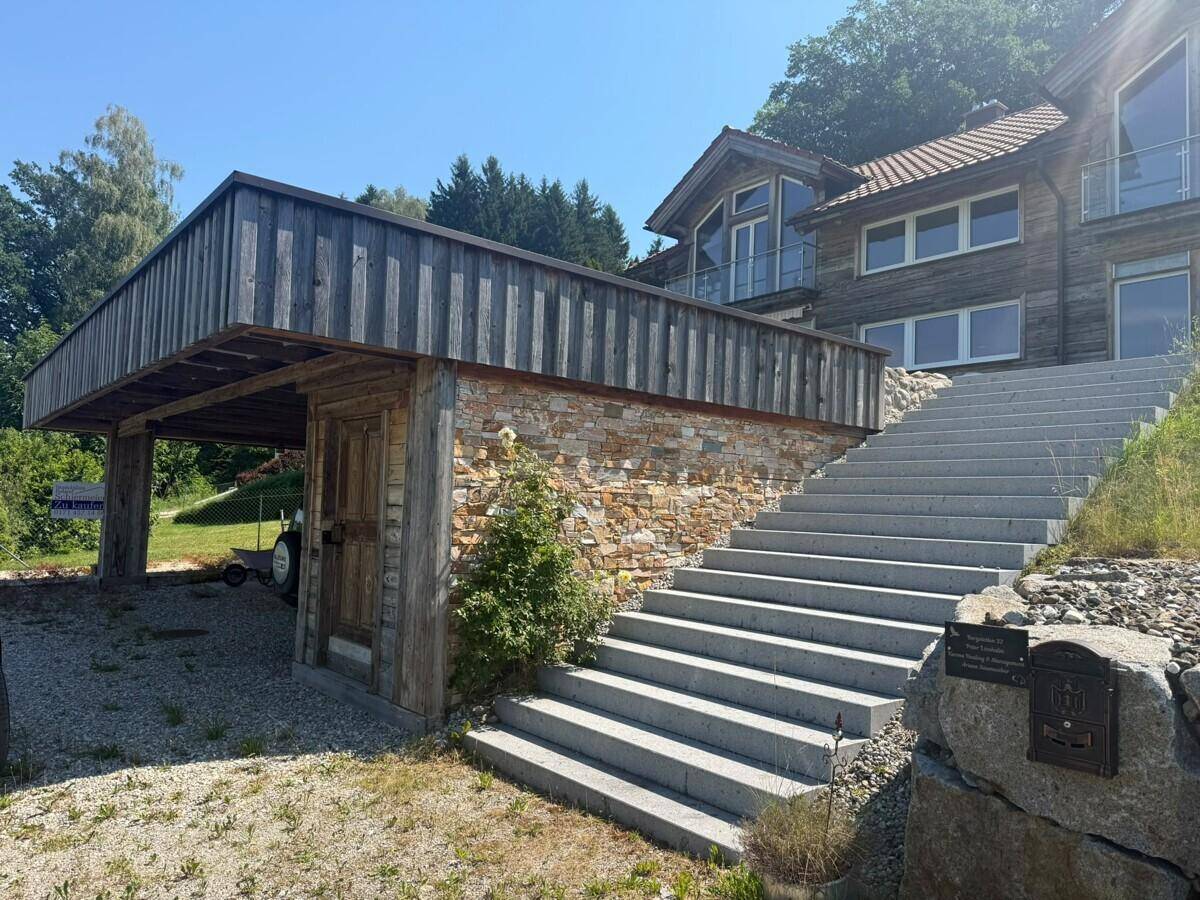 Haupteingang des Hauses mit großer Steintreppe und überdachtem Stellplatz.