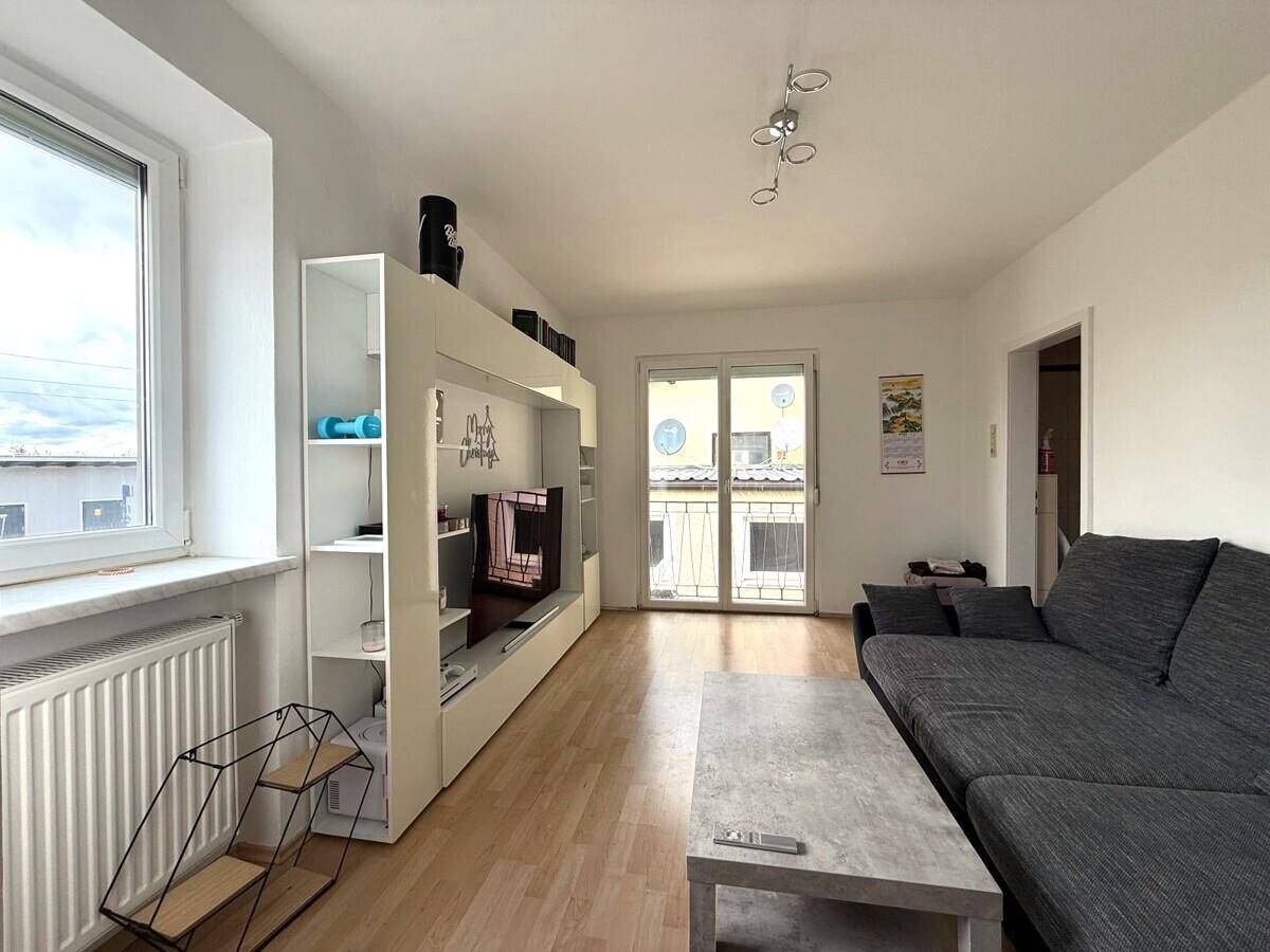 Helles Wohnzimmer mit modernem Medienregal, Laminatboden und Balkonzugang.