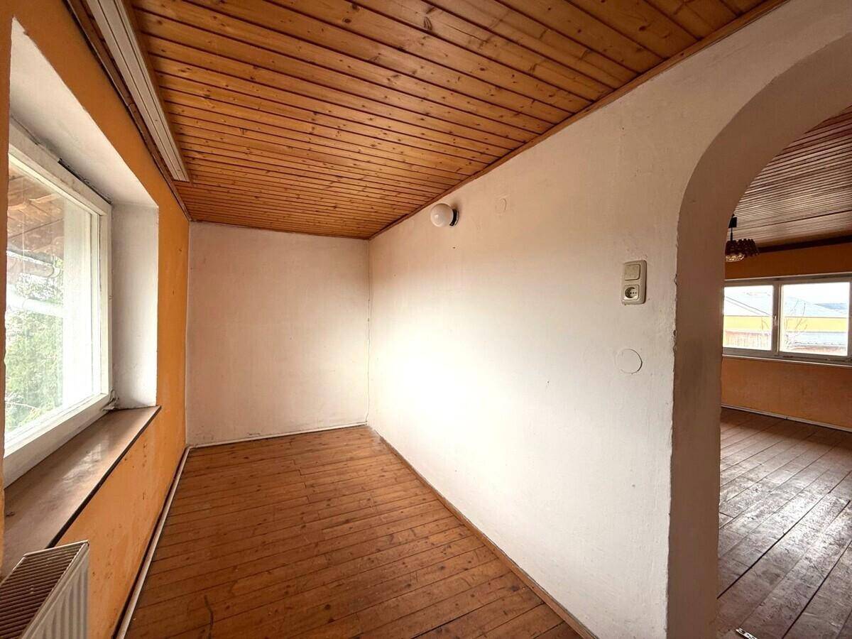 Kleiner Durchgangsbereich mit Holzdielenboden, weiß gestrichenen Wänden und einer Holzpaneeldecke.