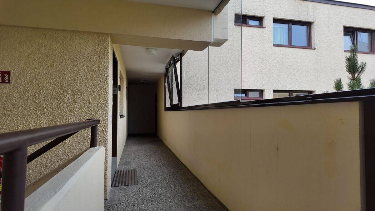 Überdachter Gang oder Loggia mit Blick auf die Gebäudefassade und weitere Fenster.