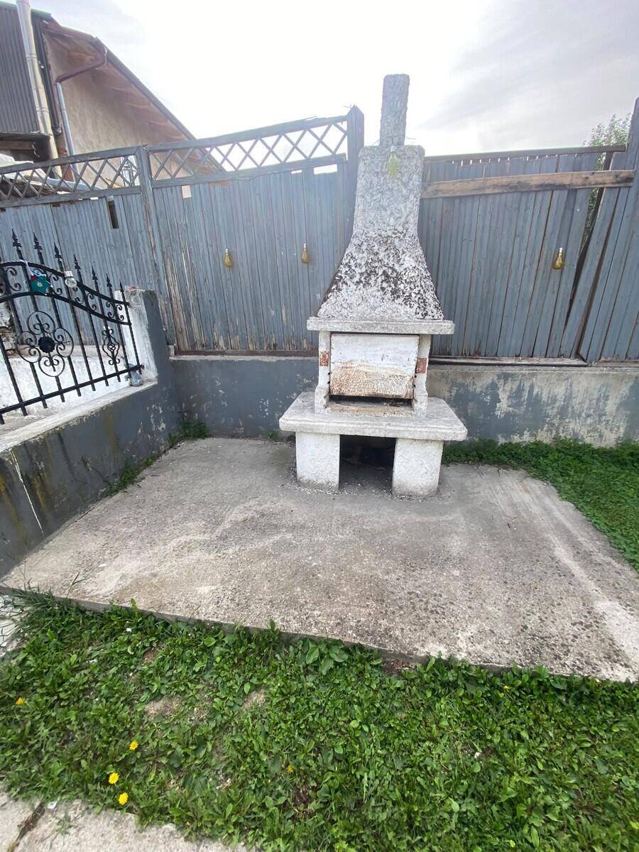 Außenbereich mit einem gemauerten Grillplatz auf einer gepflasterten Fläche im Garten.