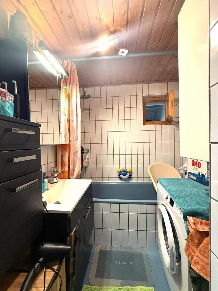 Badezimmer mit Badewanne, Dusche, Fliesenwänden und einer Holzdecke im rustikalen Stil.