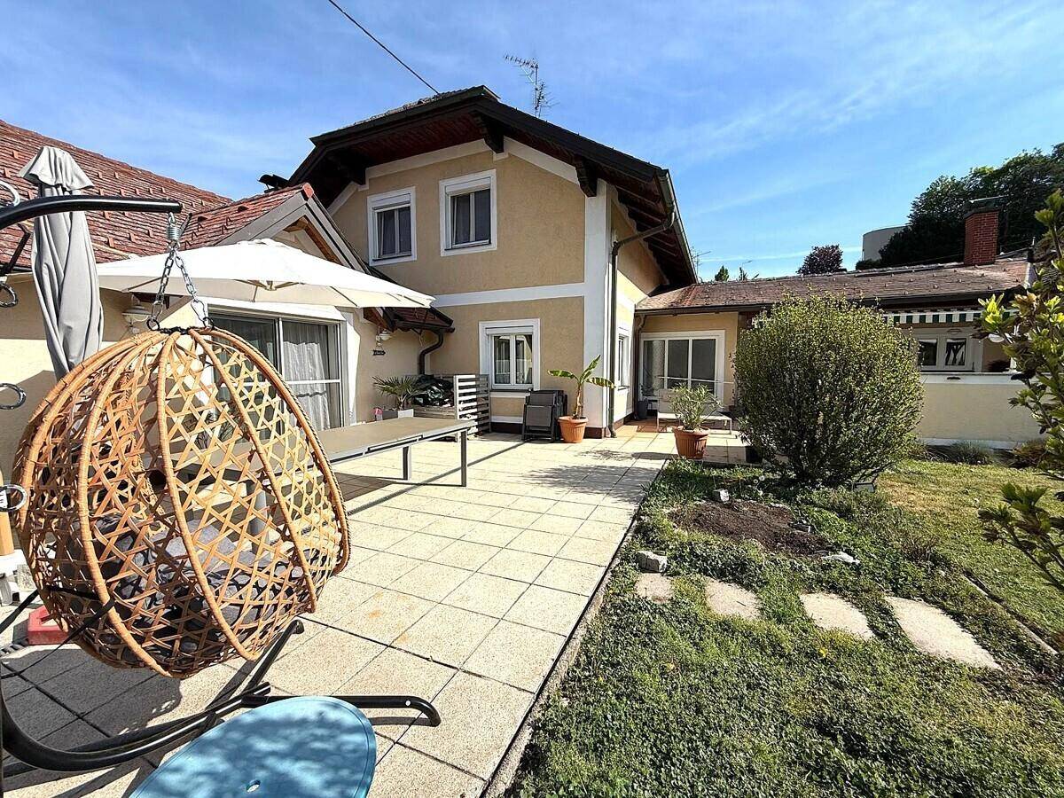 Gepflegter Garten mit Rasenfläche, Steinweg und gemütlicher Hängesessel-Schaukel neben der Terrasse.