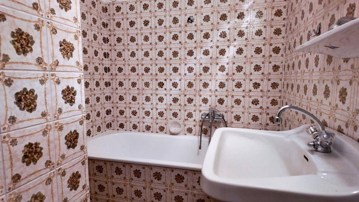Badezimmer mit gemusterten Fliesen, Badewanne und Waschbecken in traditionellem Stil.