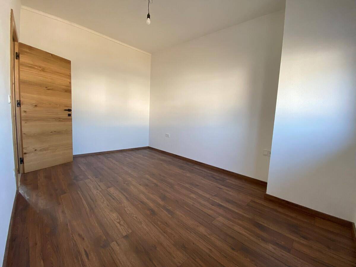 Leeres Zimmer mit warmem Holzplankenboden und moderner Holztür.