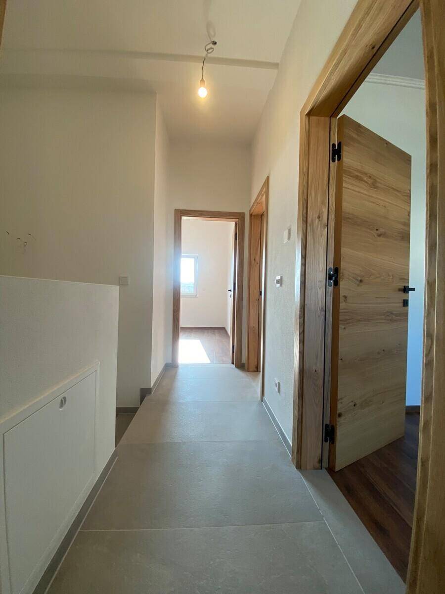 Moderner Flur mit grauen Fliesen und mehreren Holztüren zu den Zimmern.