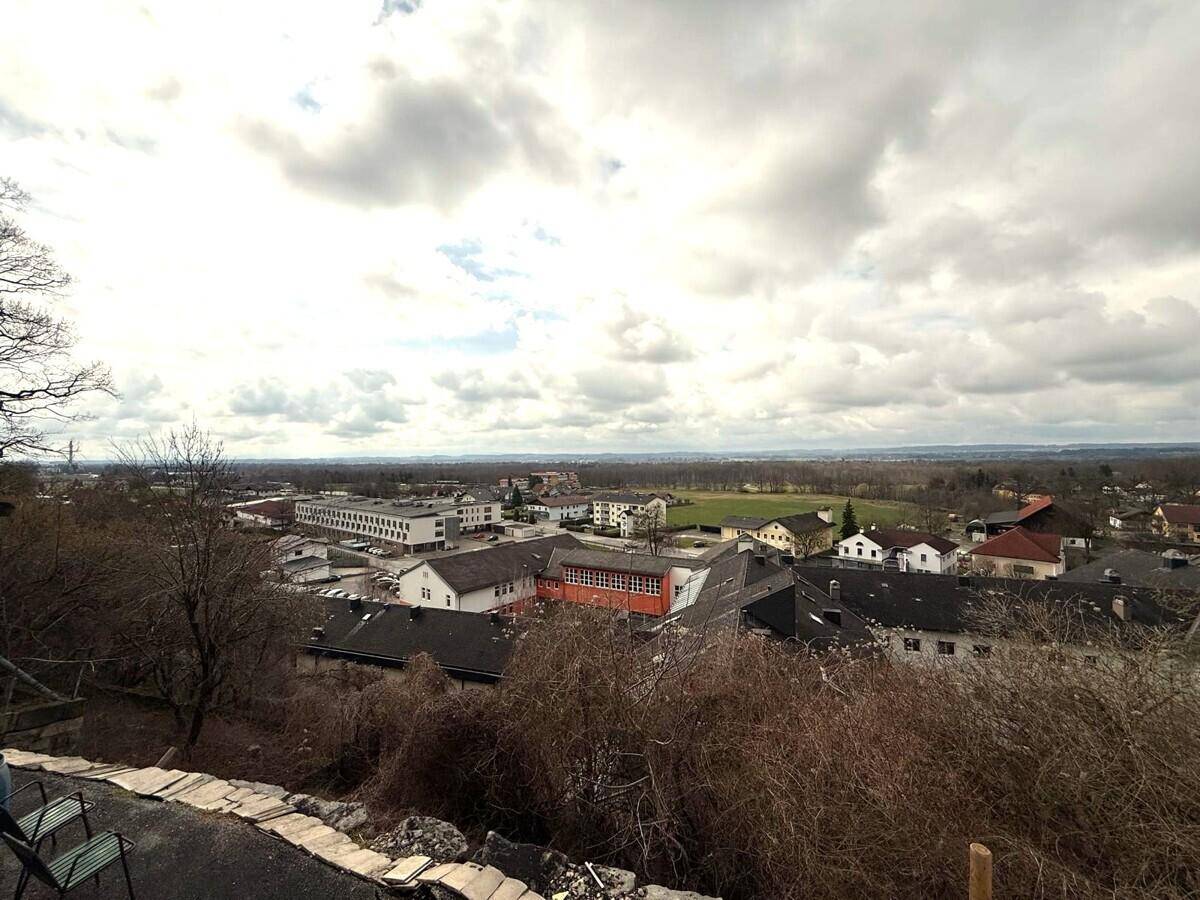 Panoramablick über eine ländliche Siedlung mit weitem Horizont unter bewölktem Himmel.