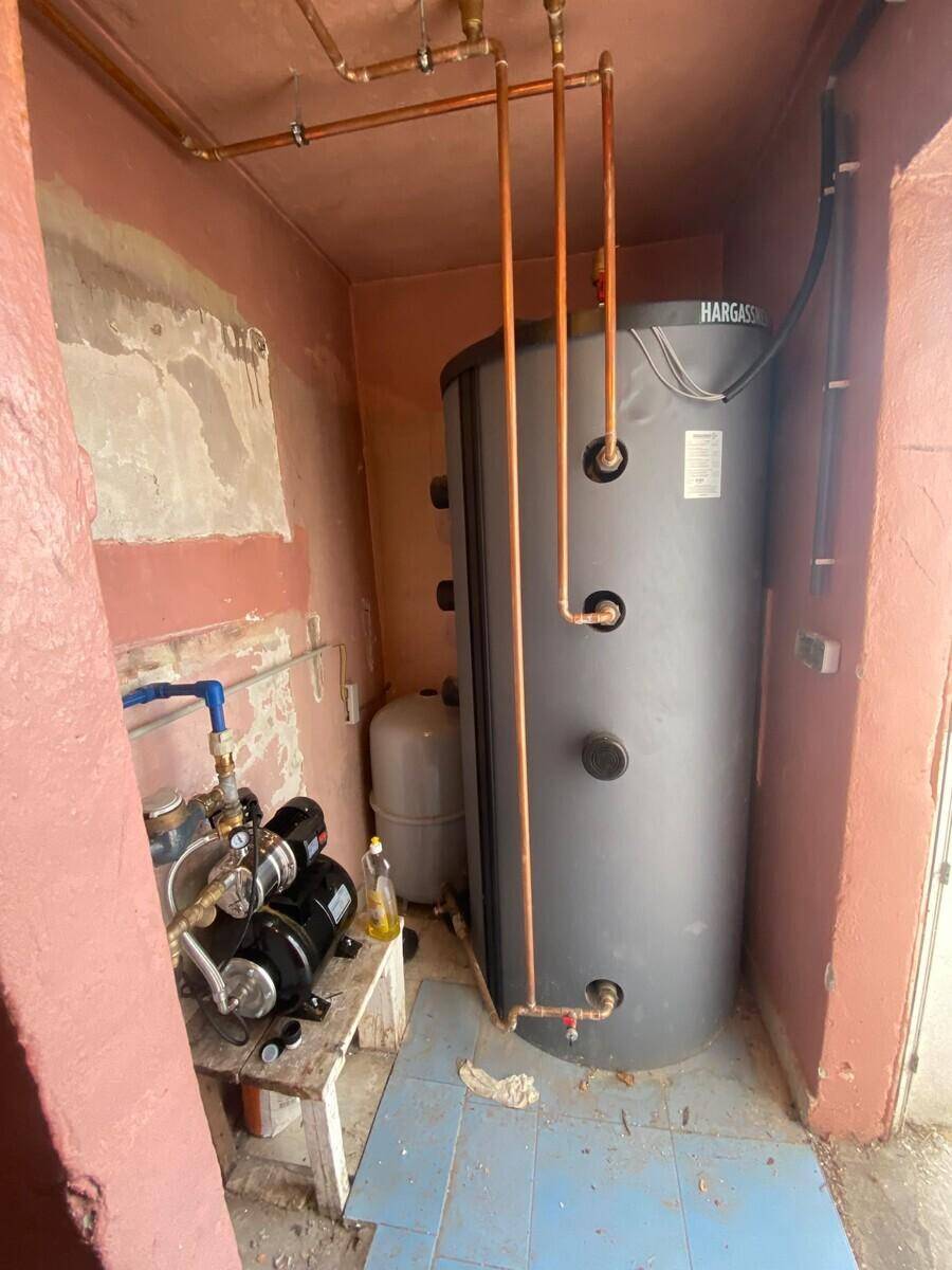Technikraum mit großem Warmwasserspeicher und Wasserpumpe für die Versorgung.