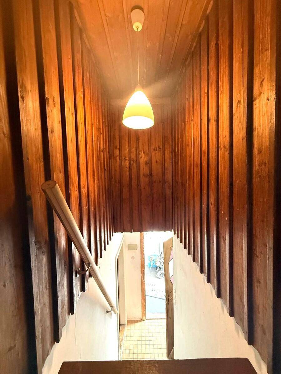 Rustikale Holztreppe mit vertäfelten Wänden und Decke, die in den unteren Bereich führt.