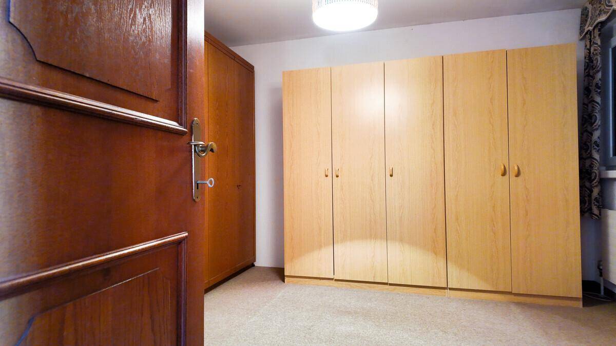 Geräumiges Zimmer mit einem großen, hellen Holzschrank und Teppichboden.