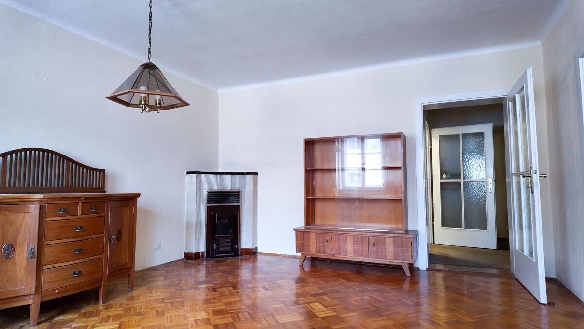 Geräumiges Wohnzimmer mit Parkettboden, einem Kamin und traditionellen Holzmöbeln.