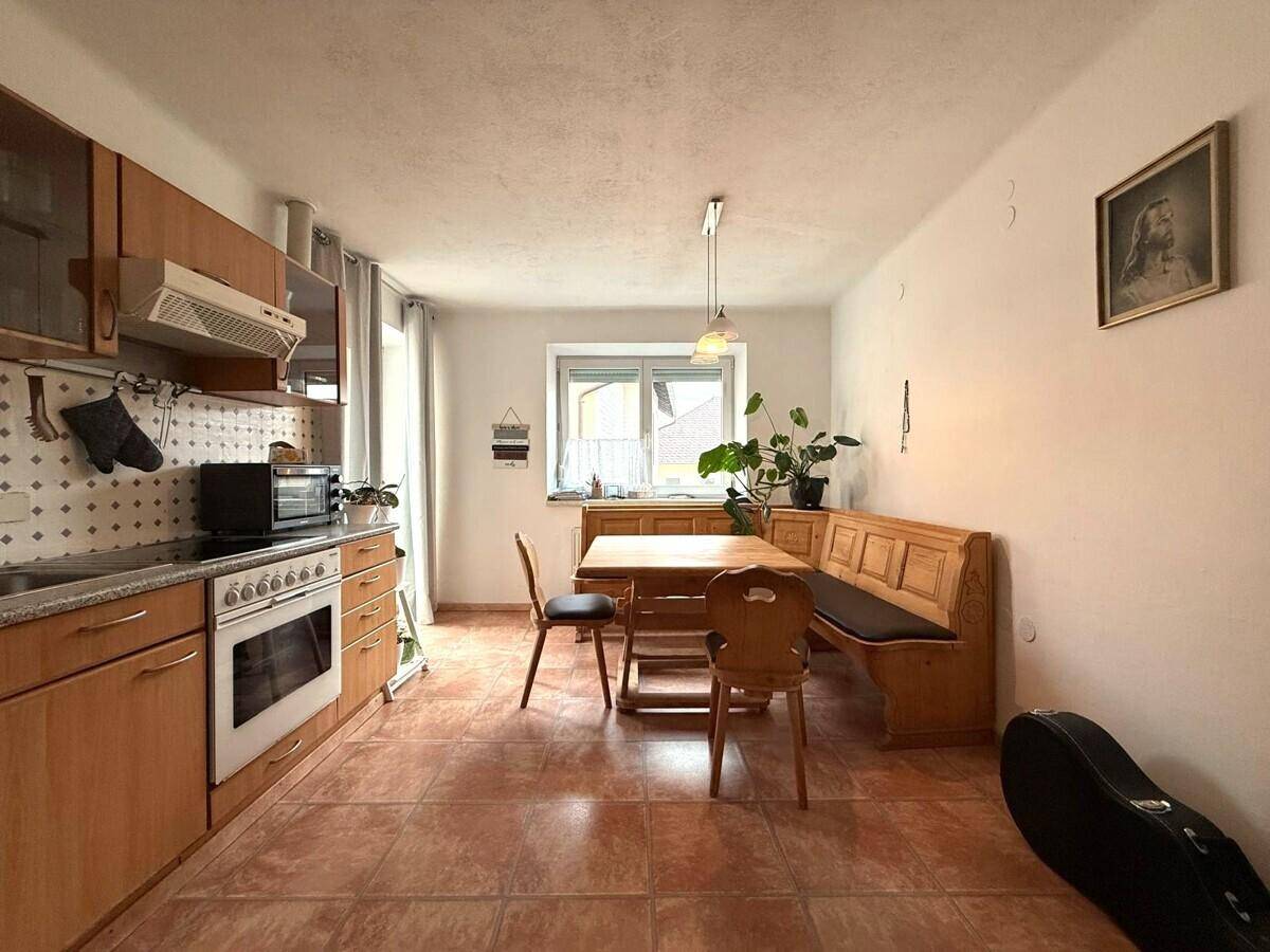 Gemütliche Wohnküche mit Holztisch, Eckbank und Fliesenboden, ideal für Mahlzeiten.