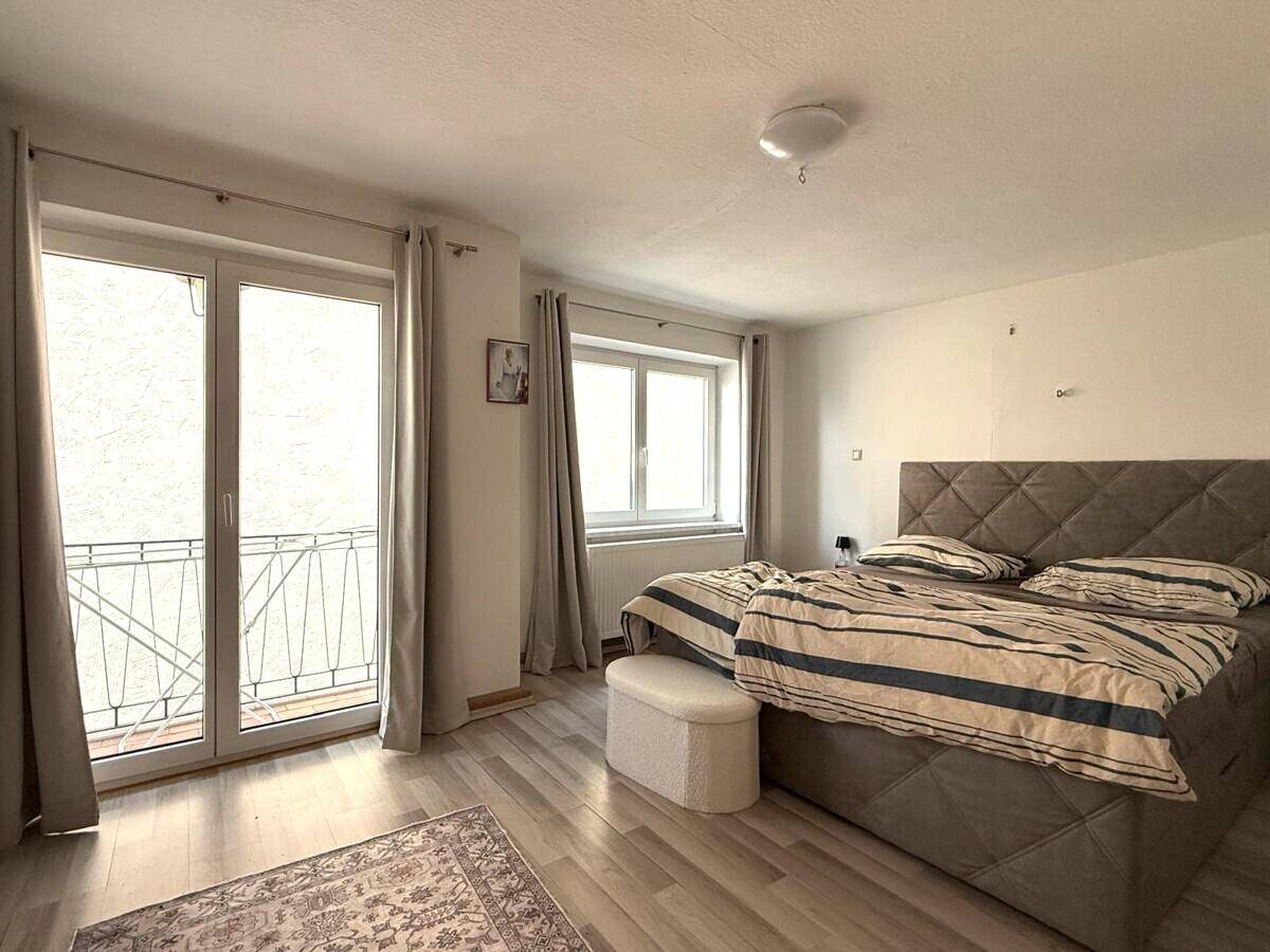 Schlafzimmer mit Doppelbett, Laminatboden und direktem Zugang zu einem Balkon.