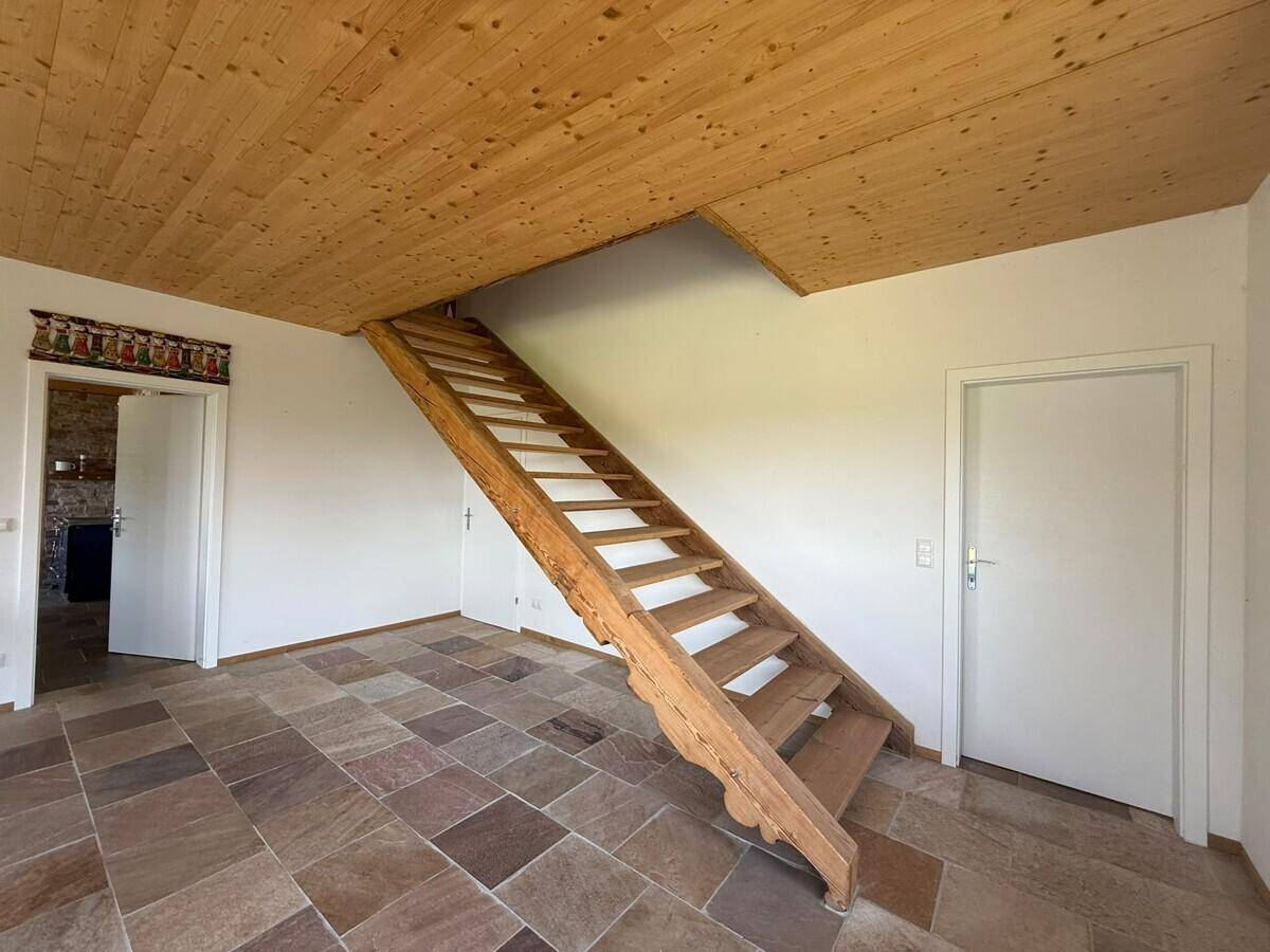 Heller Flur mit Holzdecke, Schieferboden und einer rustikalen Holztreppe.