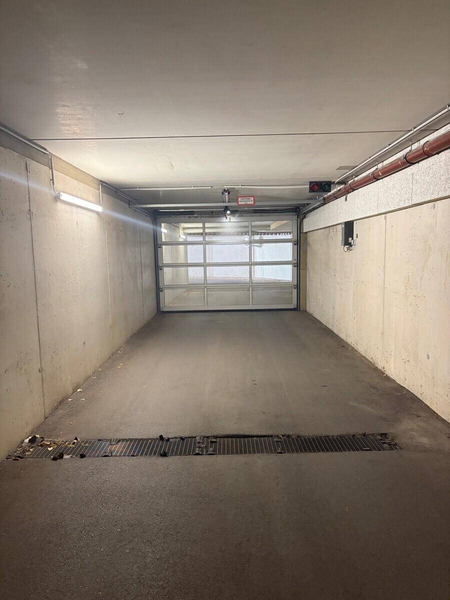 Innenansicht der Tiefgarageneinfahrt mit geschlossenem Garagentor und Beleuchtung.