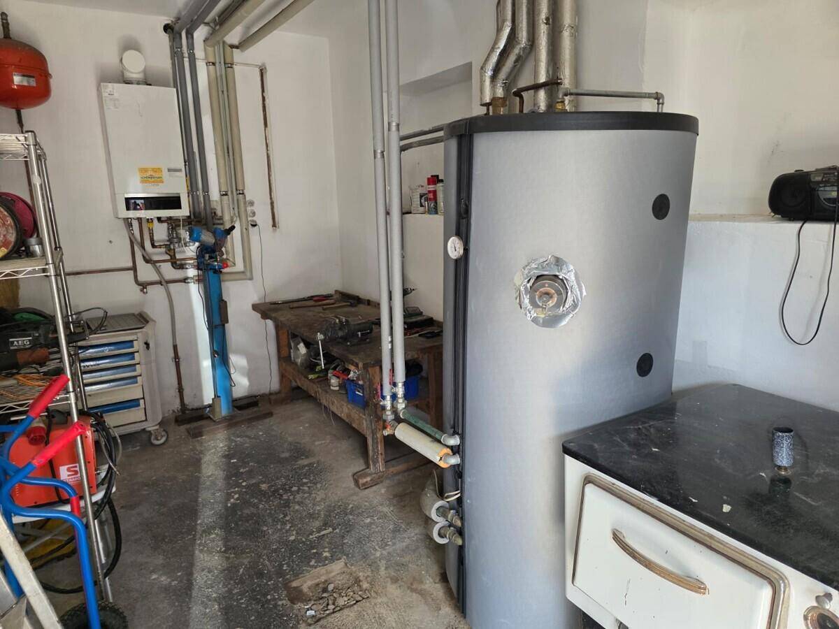 Hauswirtschaftsraum oder Werkstatt mit Warmwasserbereiter, Heizkessel und verschiedenen Werkzeugen.