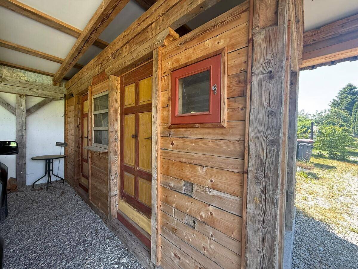 Rustikaler Holzschuppen mit kleinen Fenstern und Türen unter einem Vordach.