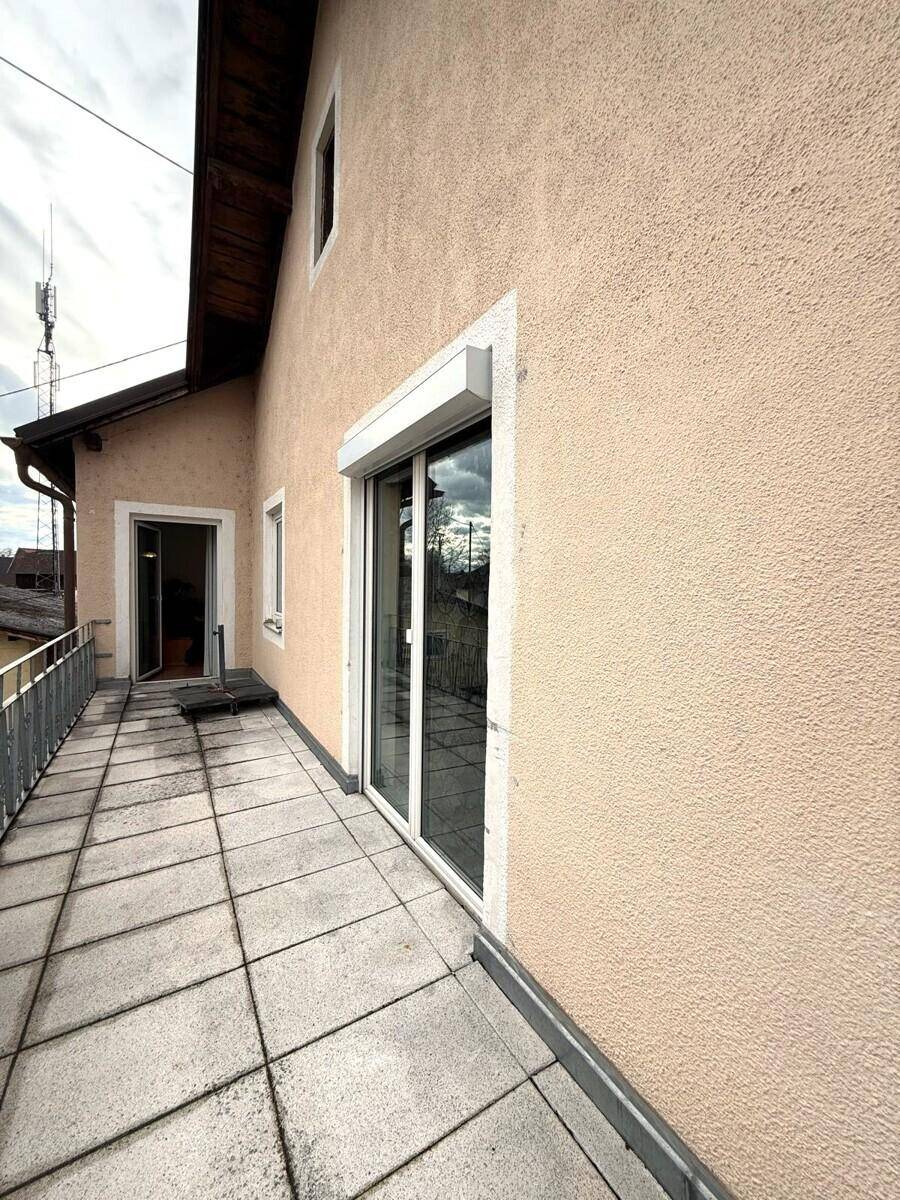 Langer Balkon mit Fliesenboden und Blick auf die Umgebung, zugänglich von Innenräumen.
