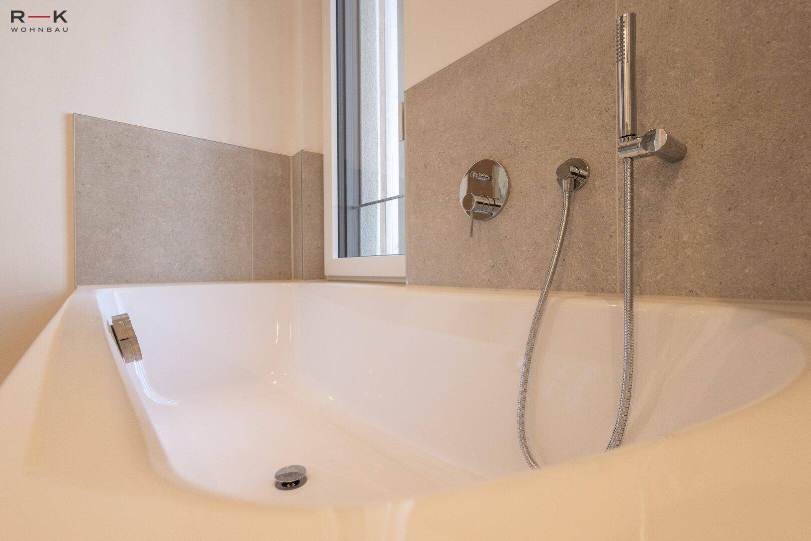 Moderne Badewanne mit integrierter Armatur und hellen Fliesen in einem zeitgemäßen Badezimmer.