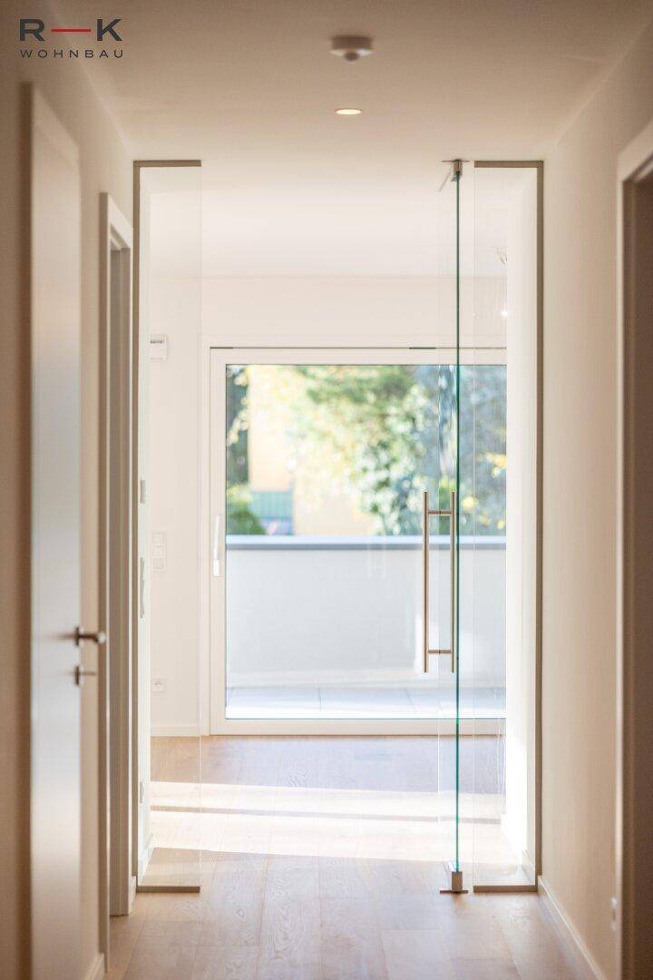 Heller Eingangsbereich mit Glastür und Blick auf den Balkon, der viel Licht hereinlässt.