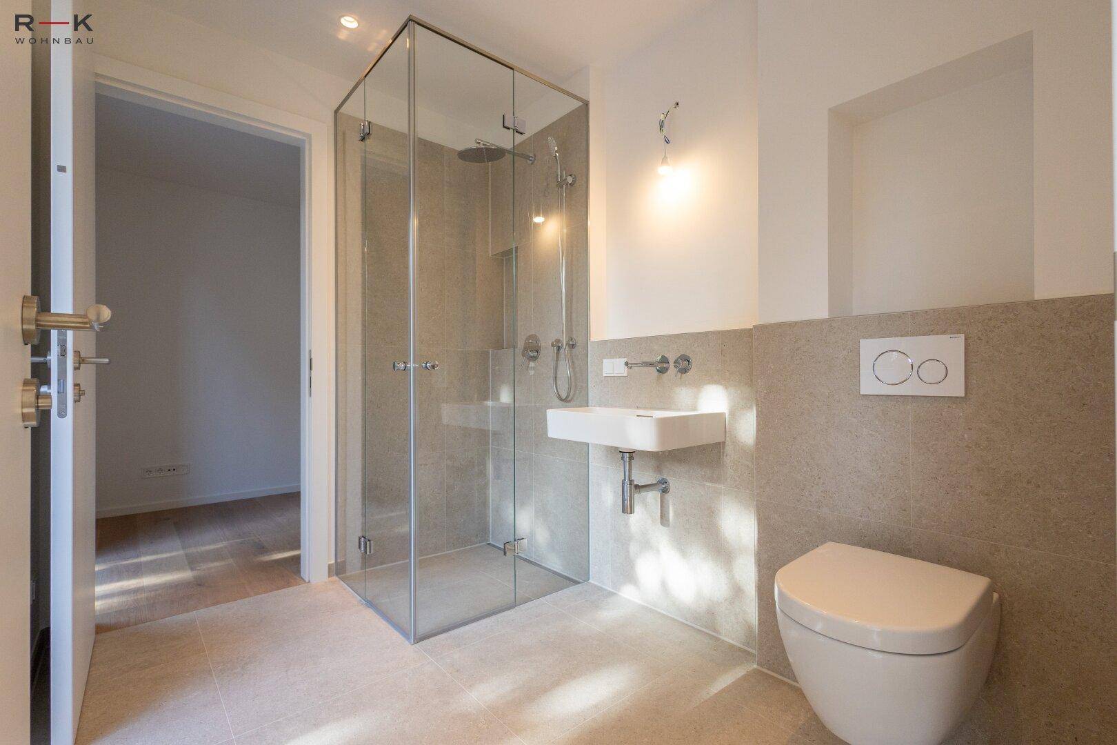Modernes Badezimmer mit ebenerdiger Dusche, wandhängendem WC und eleganten Fliesen.