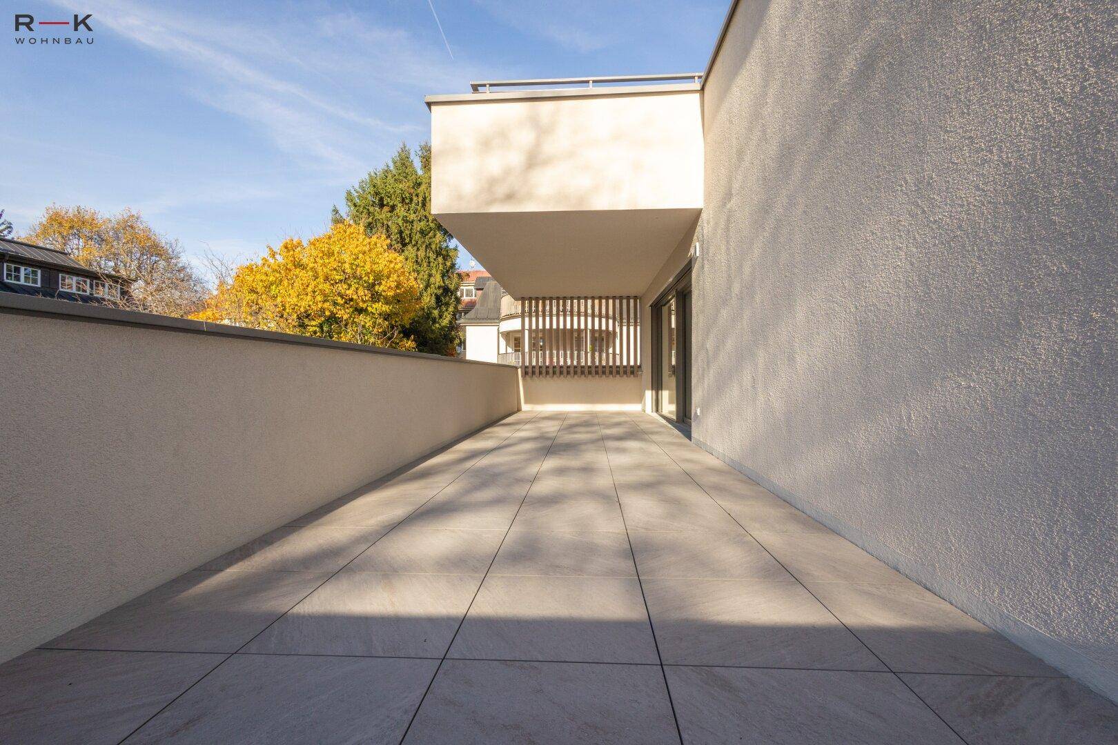 Sonniger, weitläufiger Balkon mit modernen Fliesen und einer klaren, minimalistischen Gestaltung.
