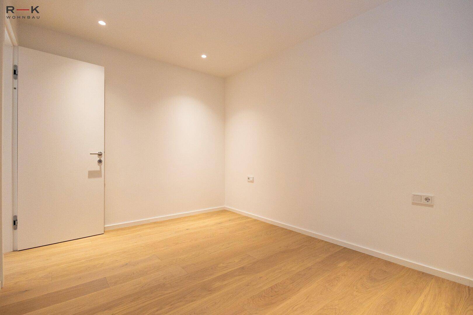 Helles Schlafzimmer mit Parkettboden und schlichter, moderner Gestaltung, bereit zur Einrichtung.