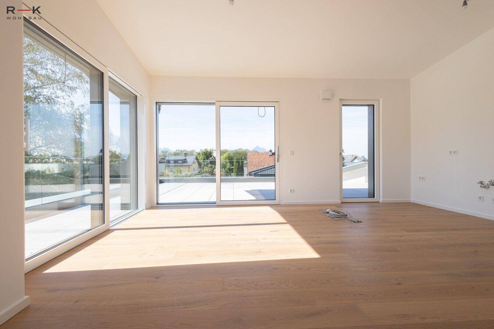 Heller, leerer Raum mit großen Schiebetüren und Zugang zu einer Dachterrasse.