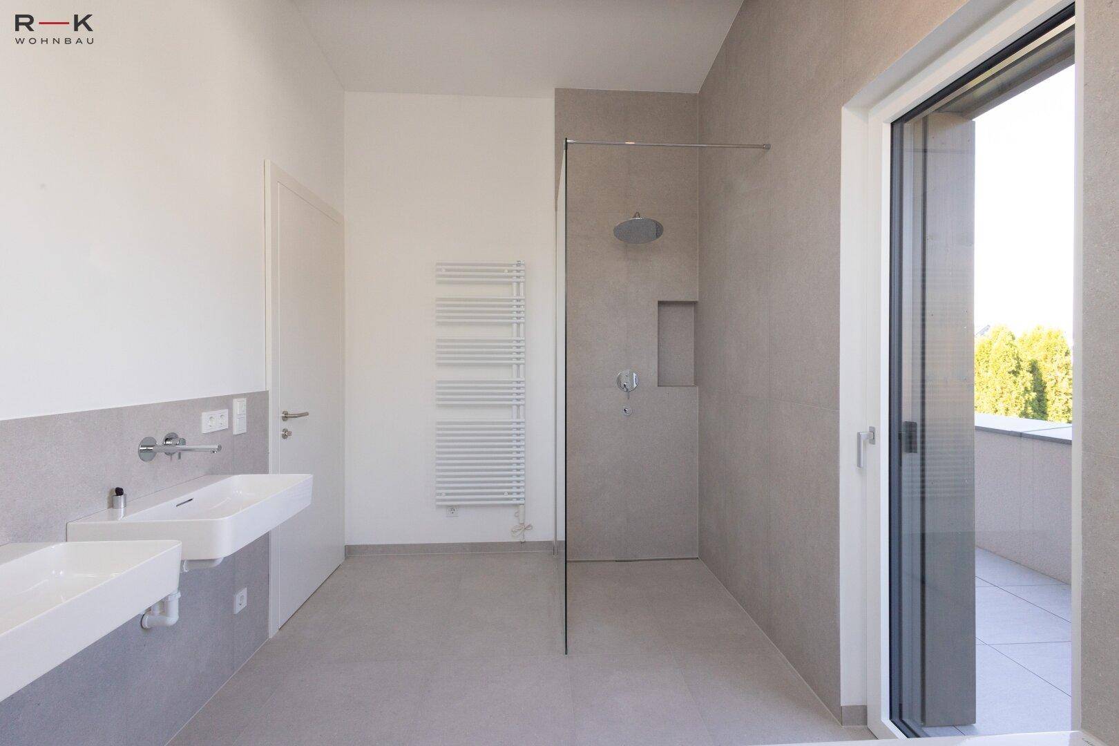 Elegantes Badezimmer mit Doppelwaschbecken, begehbarer Dusche und beheiztem Handtuchhalter.