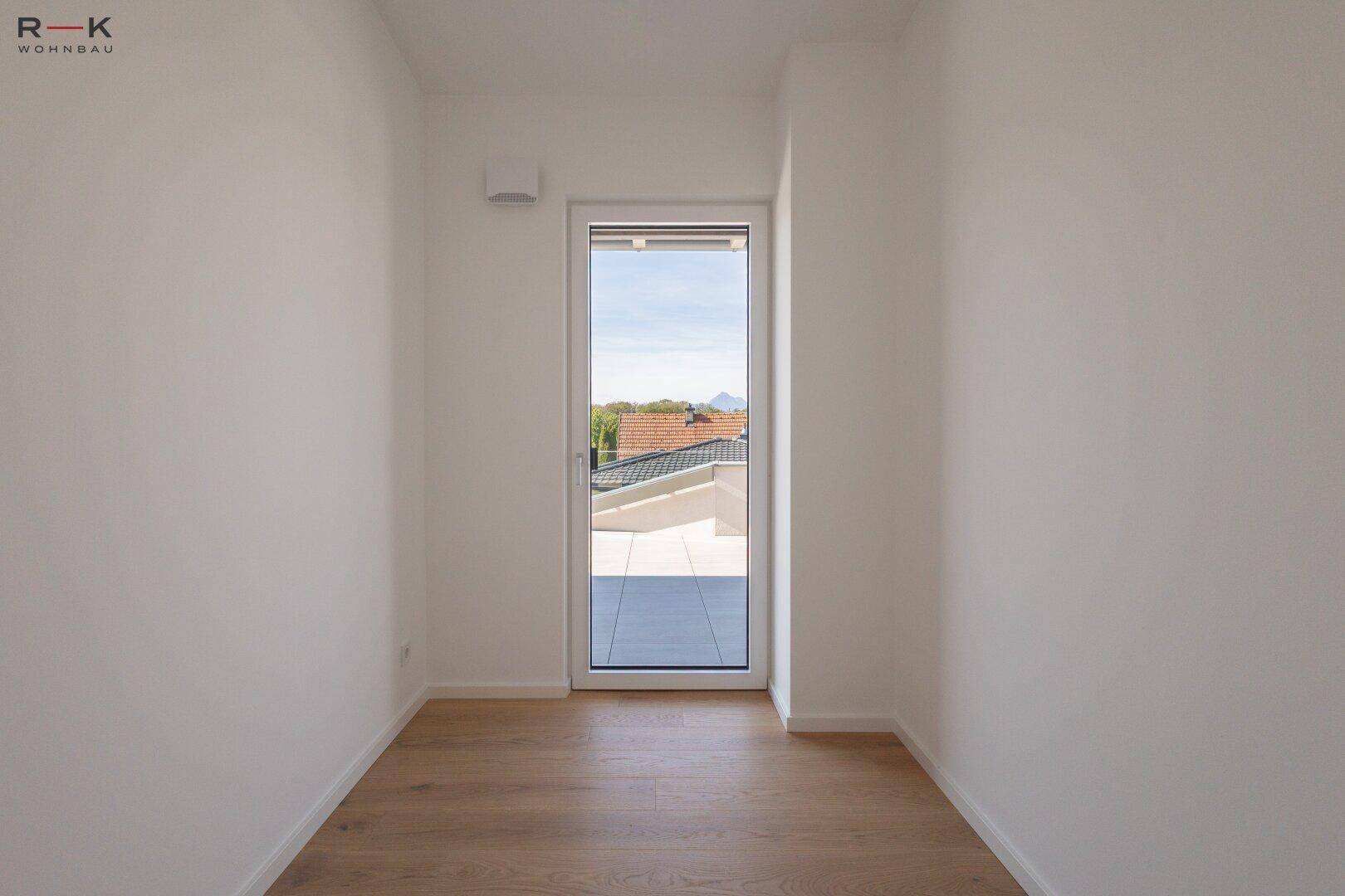 Kleinerer Raum mit Holzboden und einer Tür, die direkten Zugang zur Außenterrasse bietet.