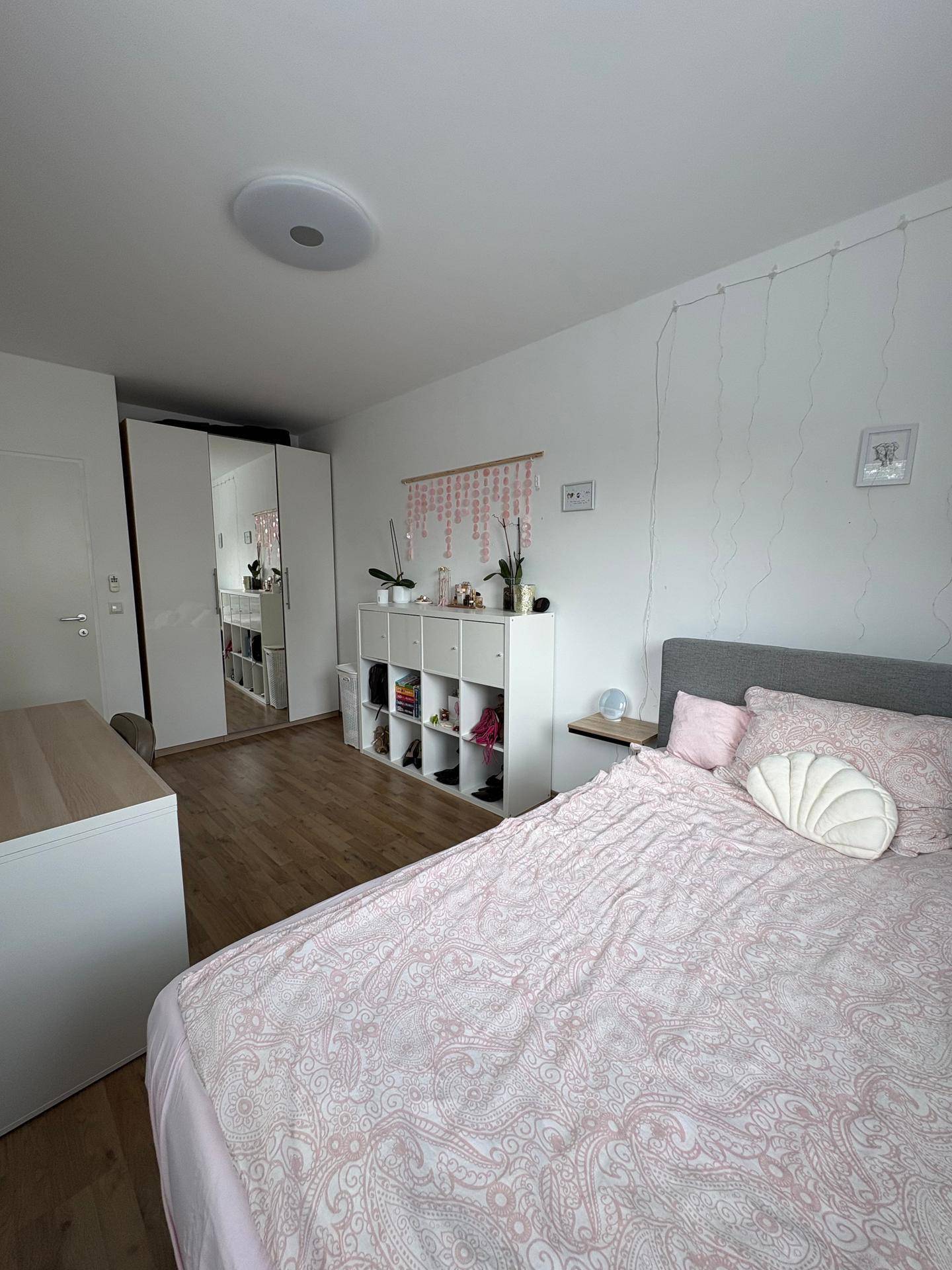 Schlafzimmer mit Einzelbett, Spiegelschrank und weißem Regal für persönliche Gegenstände.