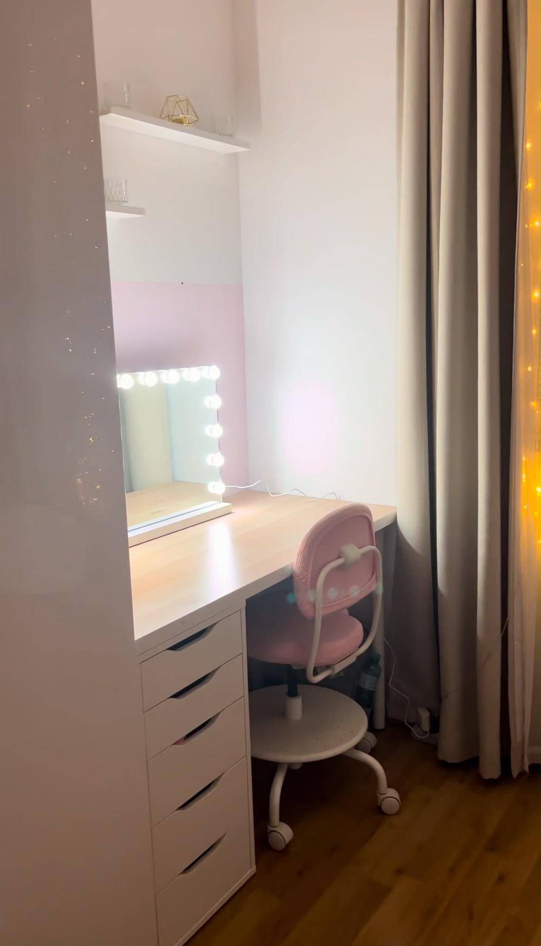 Schminkbereich im Schlafzimmer mit beleuchtetem Spiegel, Schreibtisch und Rollcontainer.