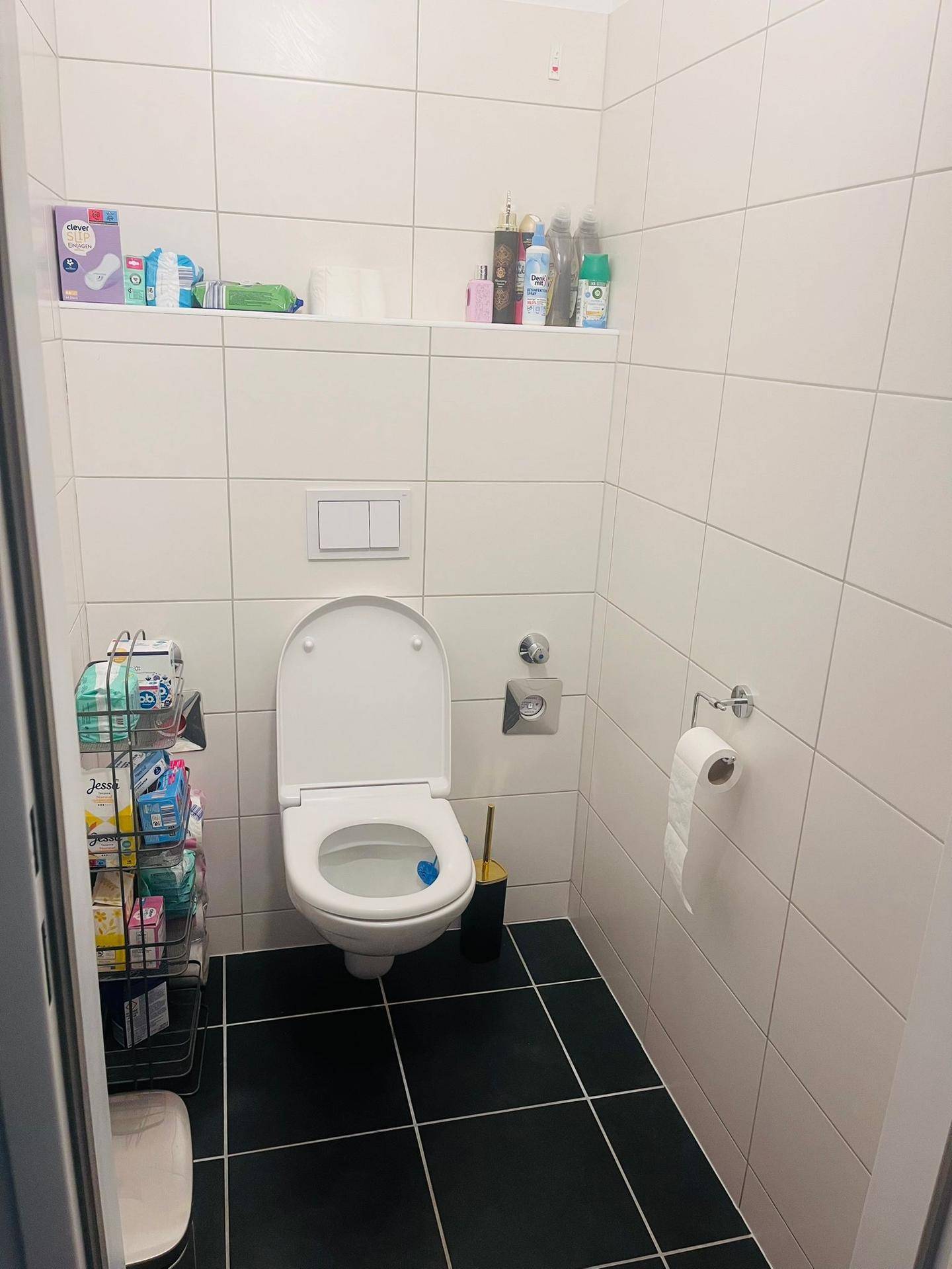 Separates WC mit Wandtoilette und weißen Fliesen, praktisch und sauber.