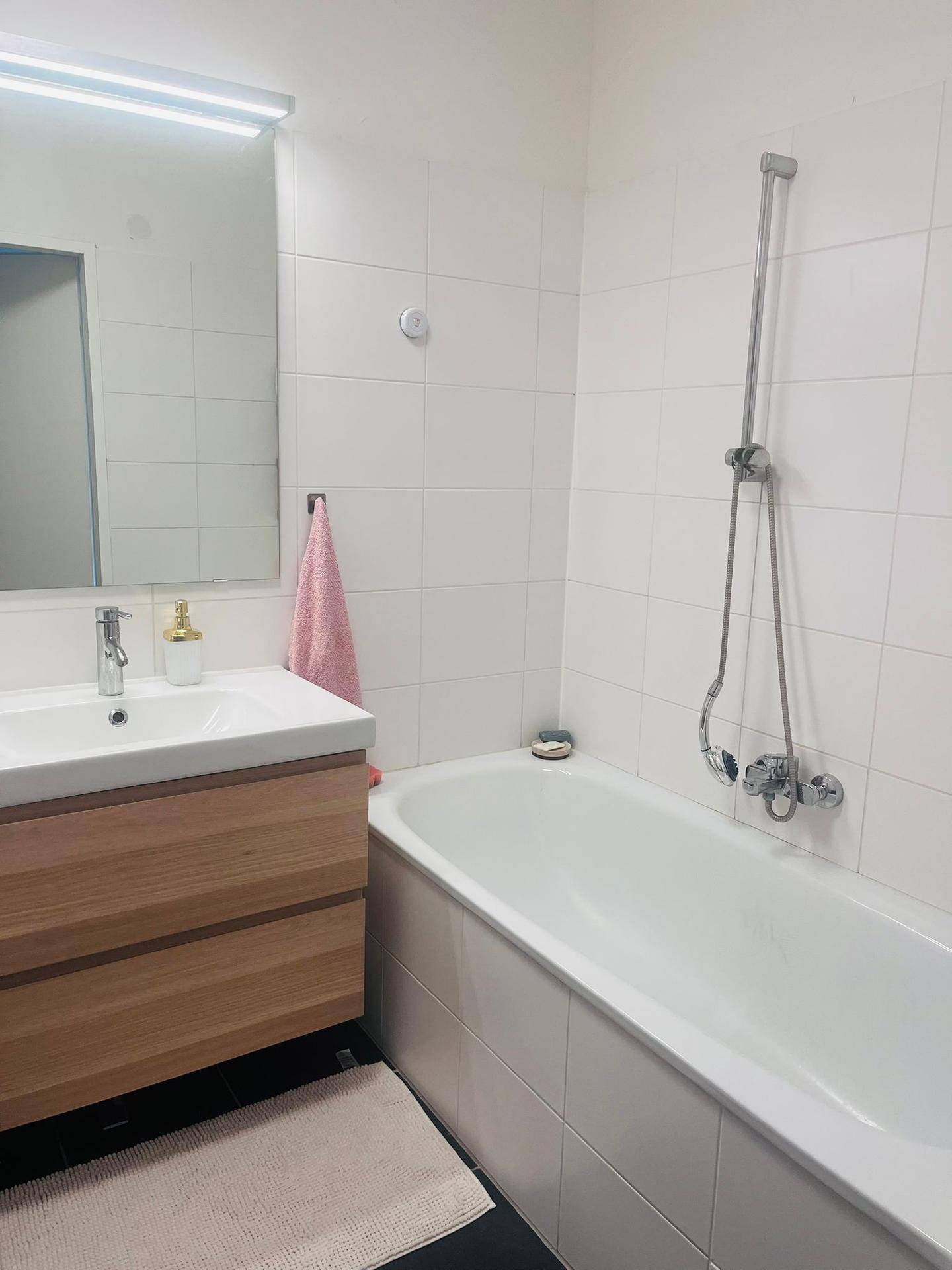 Badezimmer mit Badewanne, modernem Waschbecken und weißen Wandfliesen.