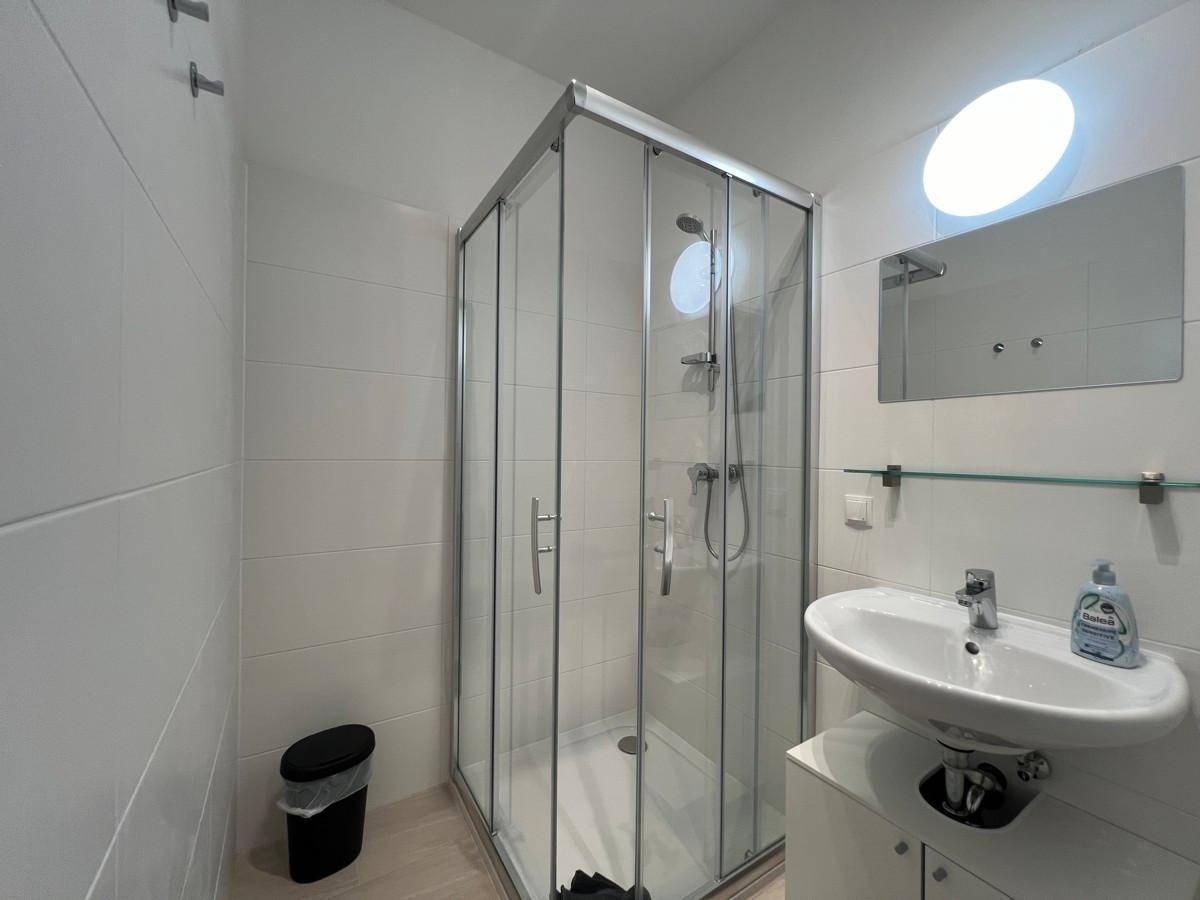 Modernes Badezimmer mit Duschkabine, Waschbecken und Wandspiegel.