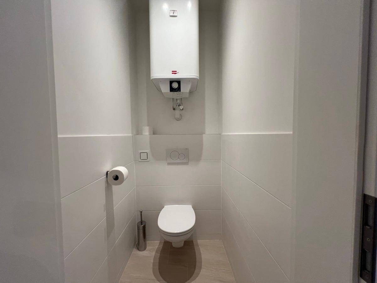 Separates WC mit wandhängender Toilette und Warmwasserboiler.