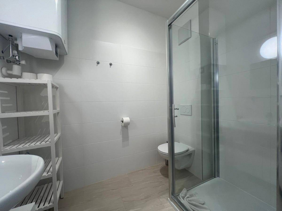 Modernes Badezimmer mit Duschkabine, wandhängendem WC und weißen Fliesen.