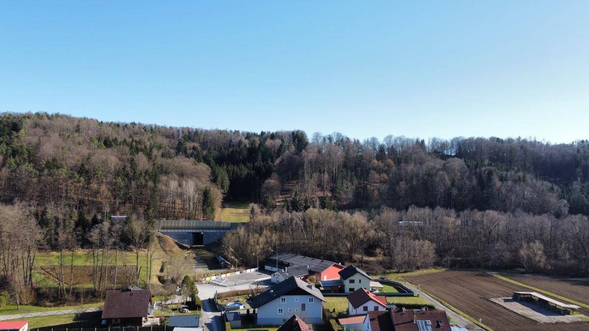 Weitläufige Landschaftsaufnahme mit bewaldeten Hügeln und ländlicher Bebauung in der Ferne.