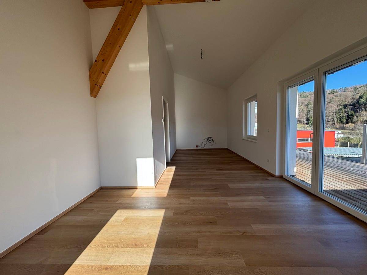 Geräumiger Wohnbereich mit Parkettboden, hohen Decken und viel Tageslicht durch große Fenster.
