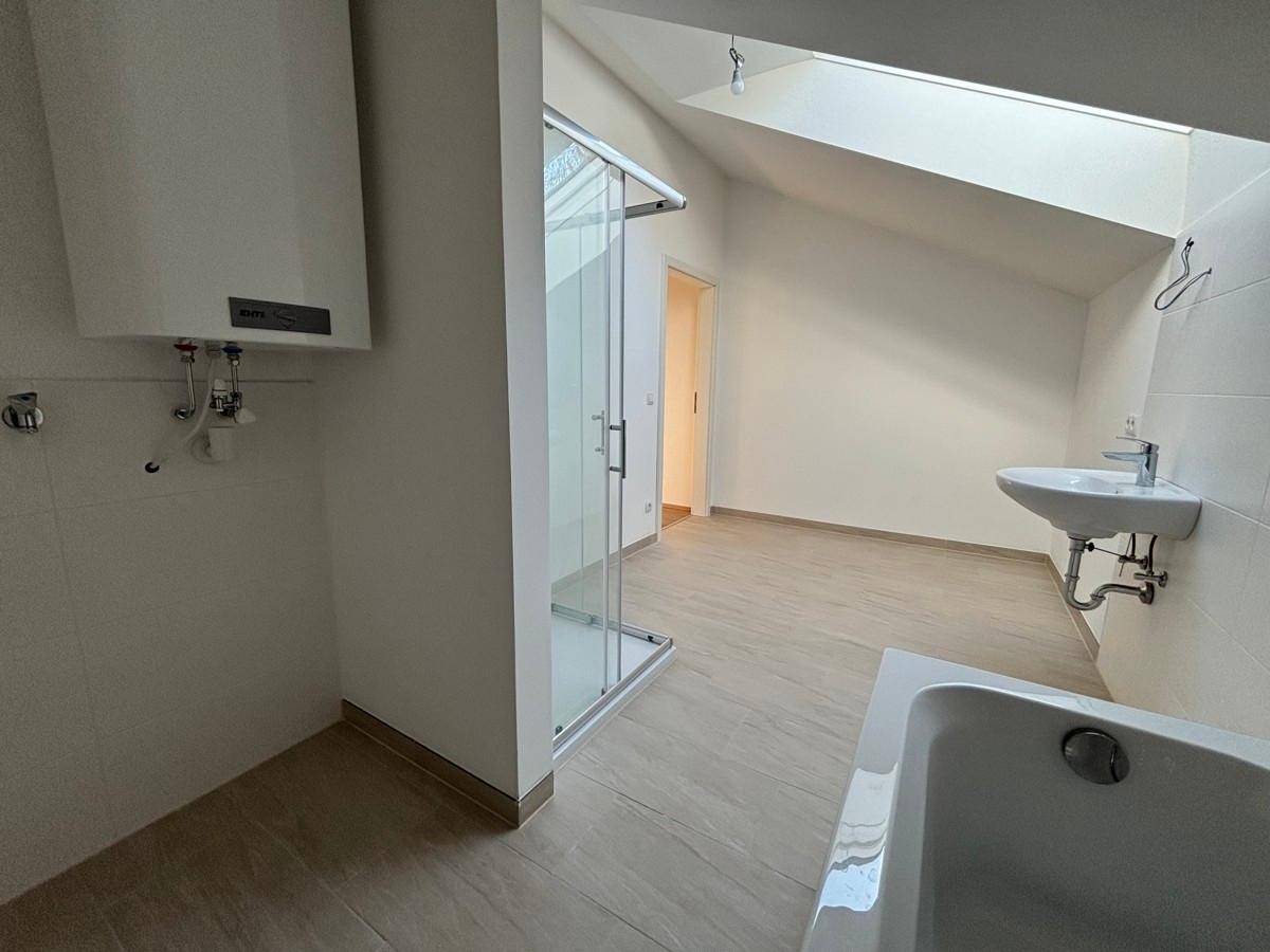 Modernes Badezimmer mit Dusche, Badewanne und Waschbecken unter einem Dachfenster.