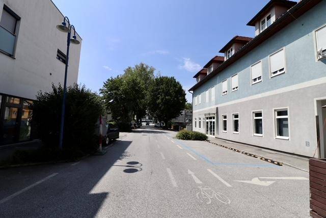 Blick auf die Straße vor dem Gebäude mit Bäumen und weiteren Gebäuden im Hintergrund.
