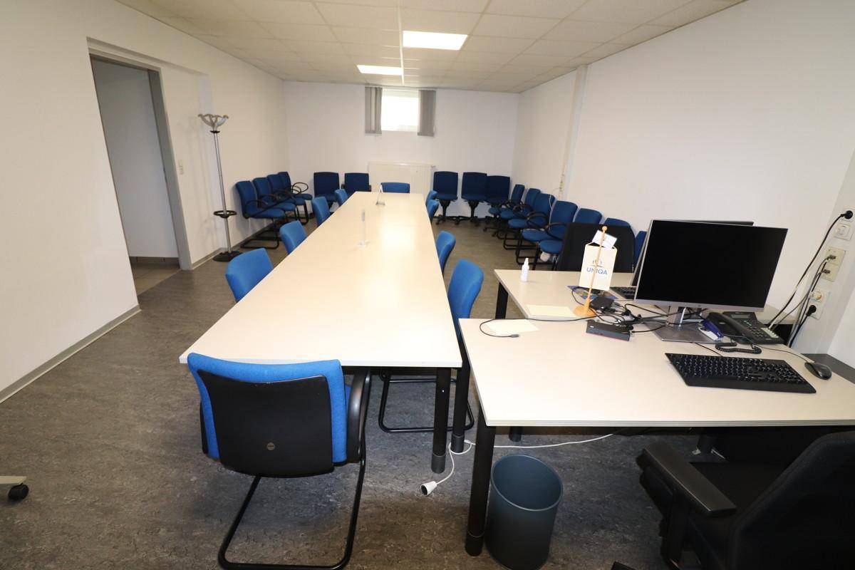 Großer Konferenzraum mit langem Tisch, vielen Stühlen und Fenstern.