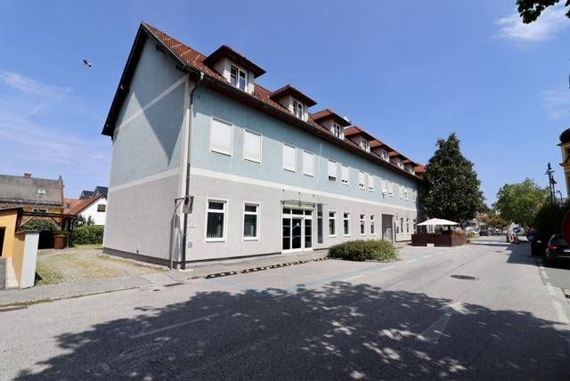 Seitenansicht des Gebäudes mit blauer Fassade, rotem Ziegeldach und umliegender Straße.