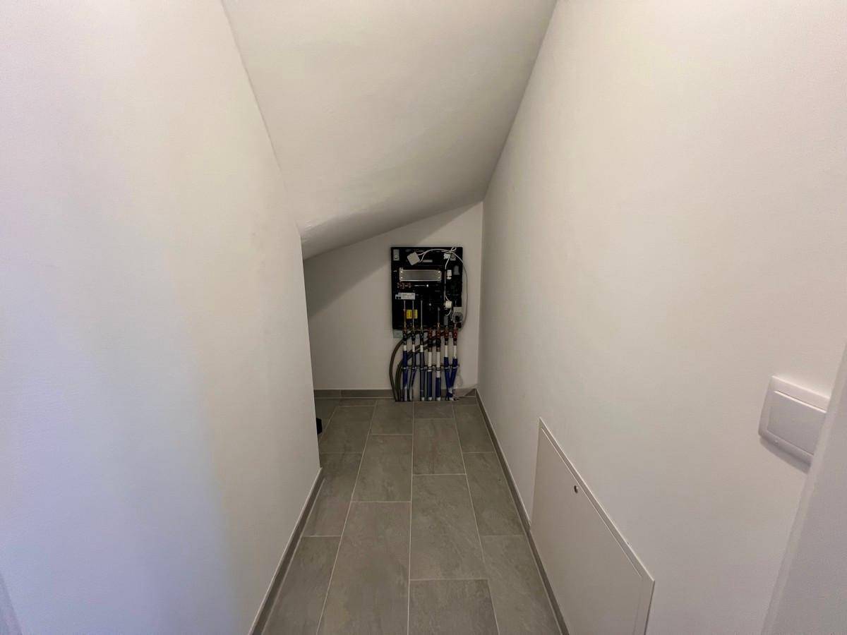 Praktischer Abstellraum mit Fliesenboden und sichtbaren Installationen unter einer Dachschräge.