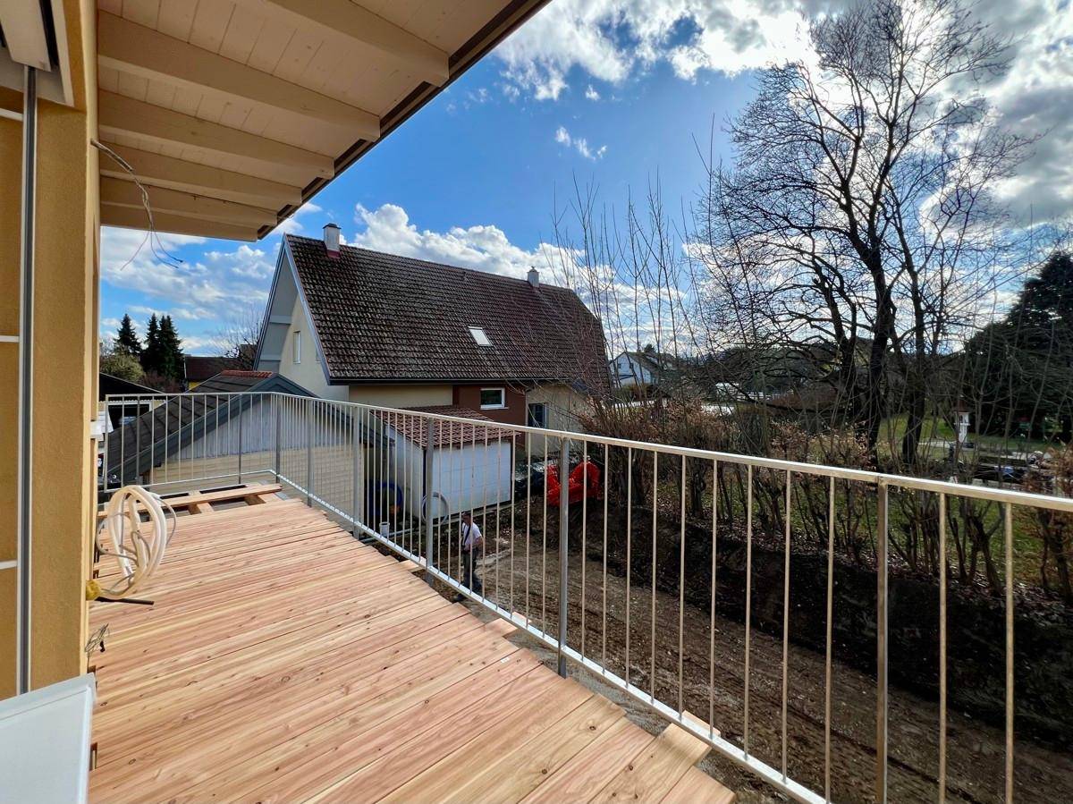 Geräumiger Balkon mit Holzbelag und Metallgeländer, bietet einen Blick auf die Umgebung.