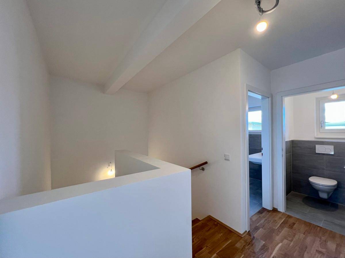 Flur im Obergeschoss mit Treppenaufgang und Blick in das moderne Badezimmer und Gäste-WC.