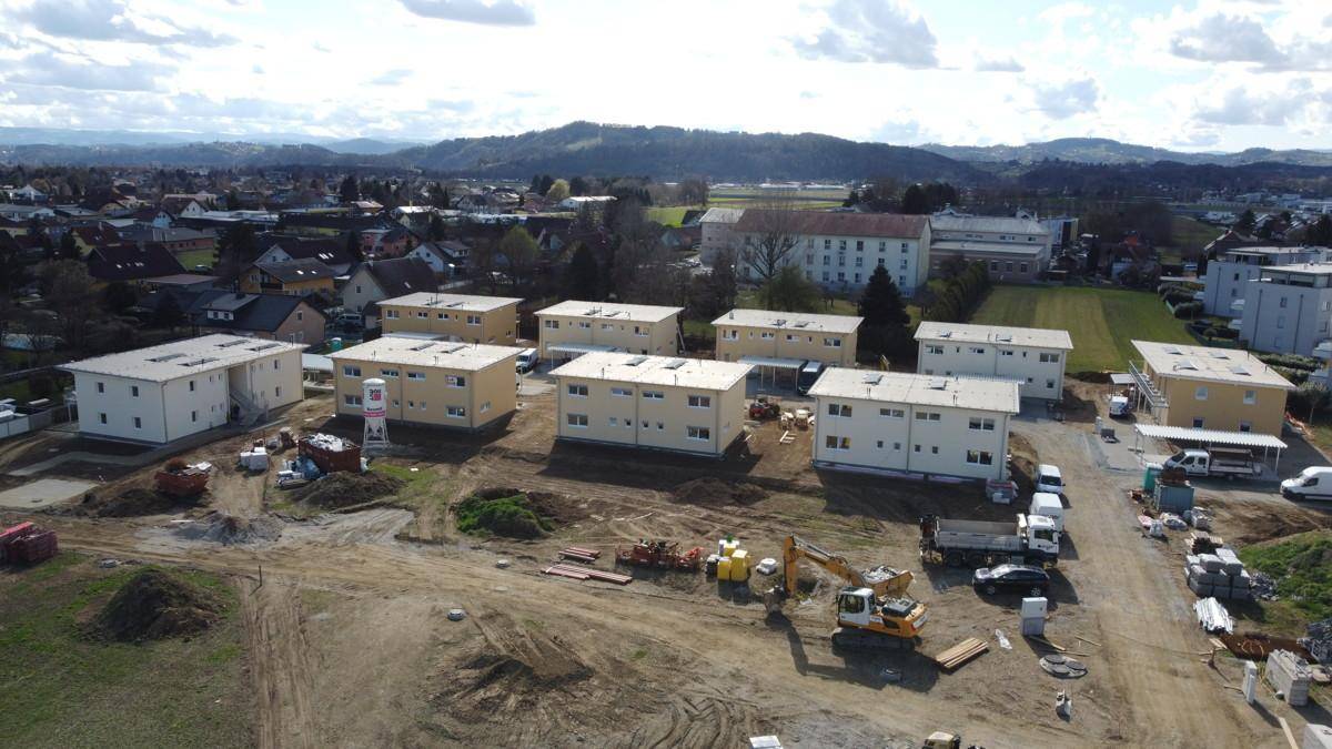 Drohnenaufnahme einer Baustelle mit mehreren im Bau befindlichen Neubauten und ländlicher Umgebung.