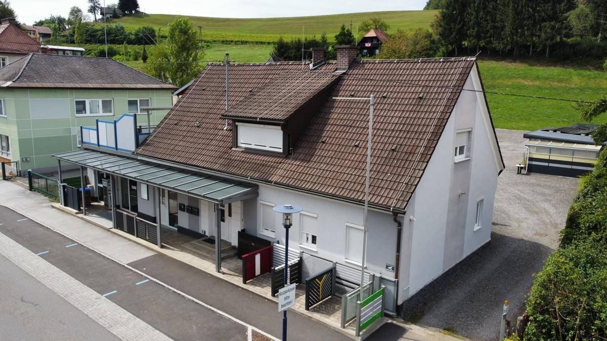 Luftaufnahme des Gebäudes mit Vordach, Parkplätzen und angrenzender Straße in ländlicher Umgebung.