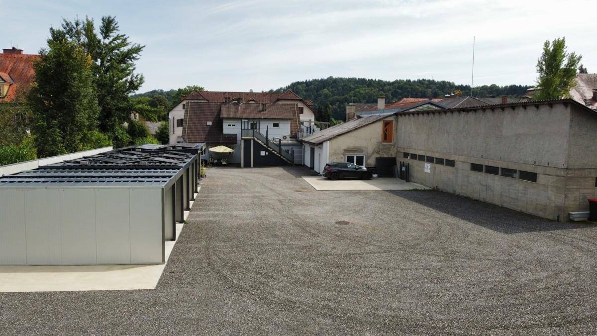 Großzügiger Außenbereich mit Schotterparkplatz, Carports und Blick auf die bewaldeten Hügel.